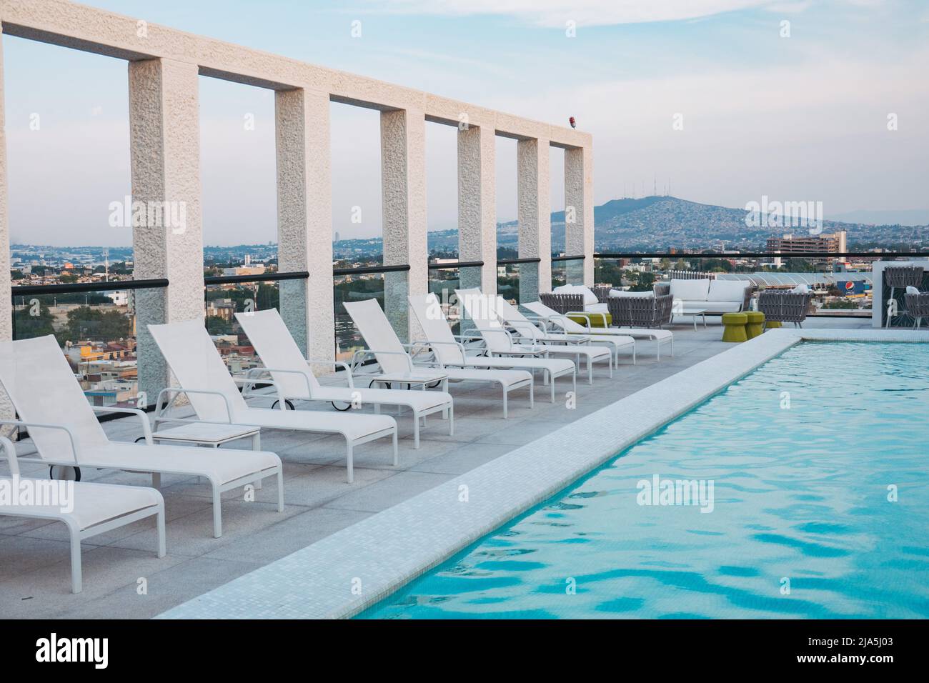 Liegestühle säumen einen Pool auf dem Dach eines modernen Apartments in der Stadt Guadalajara, Mexiko Stockfoto