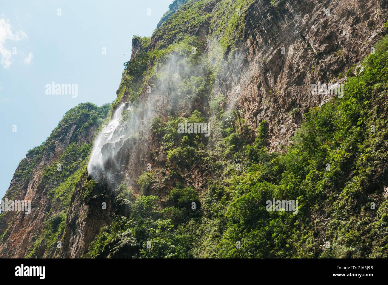 Im Sumidero Canyon, einem tiefen natürlichen Canyon, der bei Touristen im mexikanischen Bundesstaat Chiapas beliebt ist, sprüht ein nebliger Wasserfall von einer Felswand Stockfoto