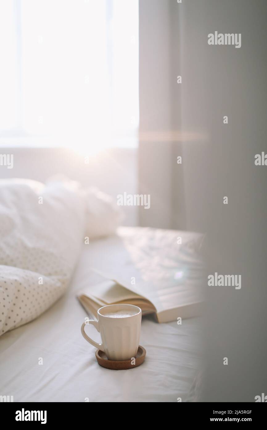 Lesen und Frühstück im Bett. Kaffeetasse und ein Buch im Bett. Gemütlicher sonniger Morgen zu Hause. Stockfoto
