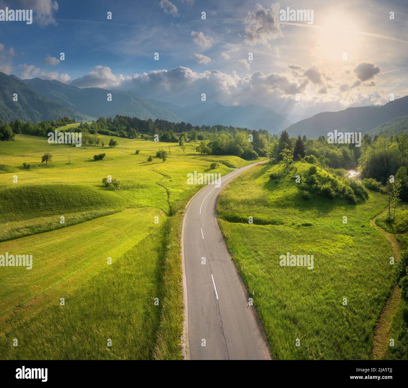 Luftaufnahme der Straße in grünen Wiesen und hils bei Sonnenuntergang im Sommer Stockfoto