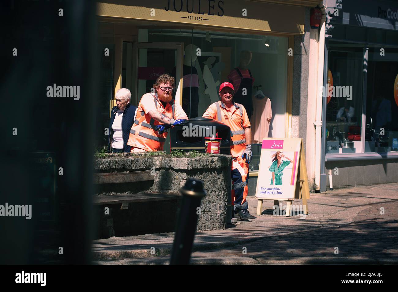 Zwei ratsarbeiter in Day-Glo orange Arbeitskleidung standen auf der Straße in der Nähe eines Mülltonnen in Truro, Cornwall. Stockfoto