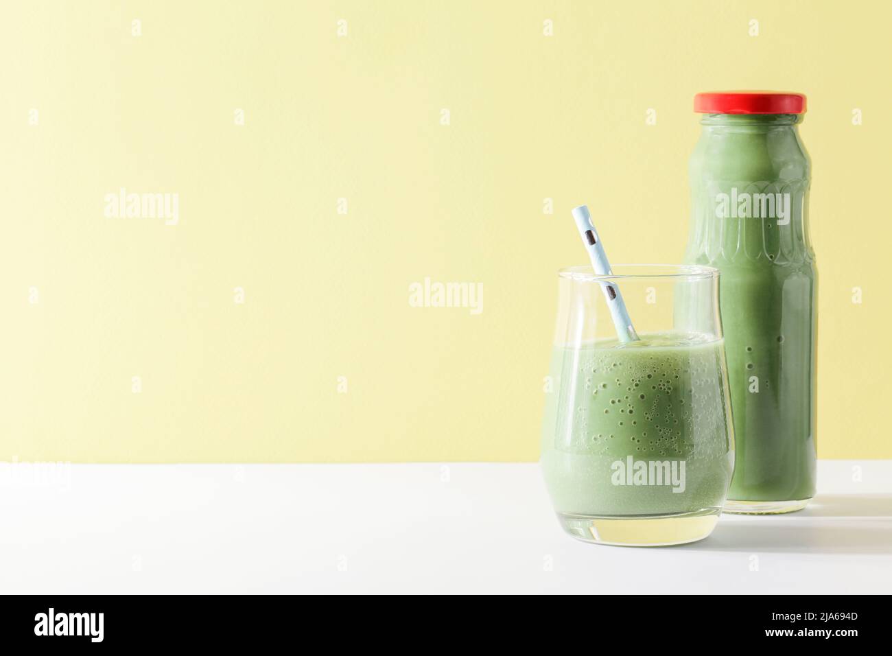 Gesunder grüner Smoothie im Glas, Flasche mit Stroh auf gelbem Hintergrund. Vegetarische gesunde Lebensweise Konzept.erfrischendes Getränk. Schnelle Snack.Copy Raum Stockfoto