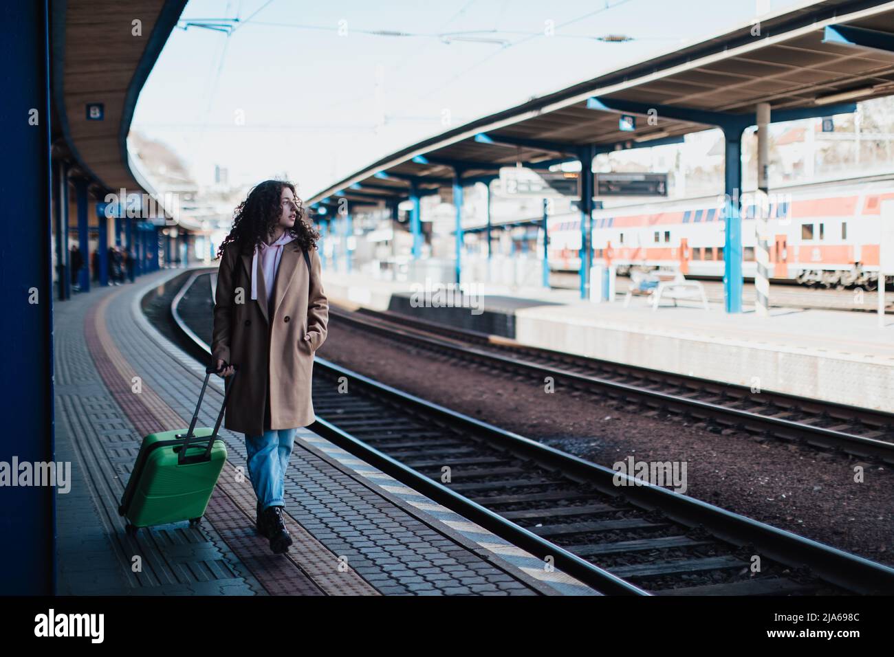 Glückliche junge Reisende Frau mit Gepäck, die am Bahnhofsplatz auf den Zug wartete Stockfoto