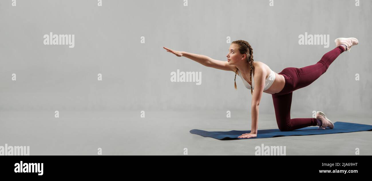 Sport Frau in der Mode Sport Kleidung arbeiten gegen graue Wand, tun Yoga,  Pilates balancing Übung Stockfotografie - Alamy