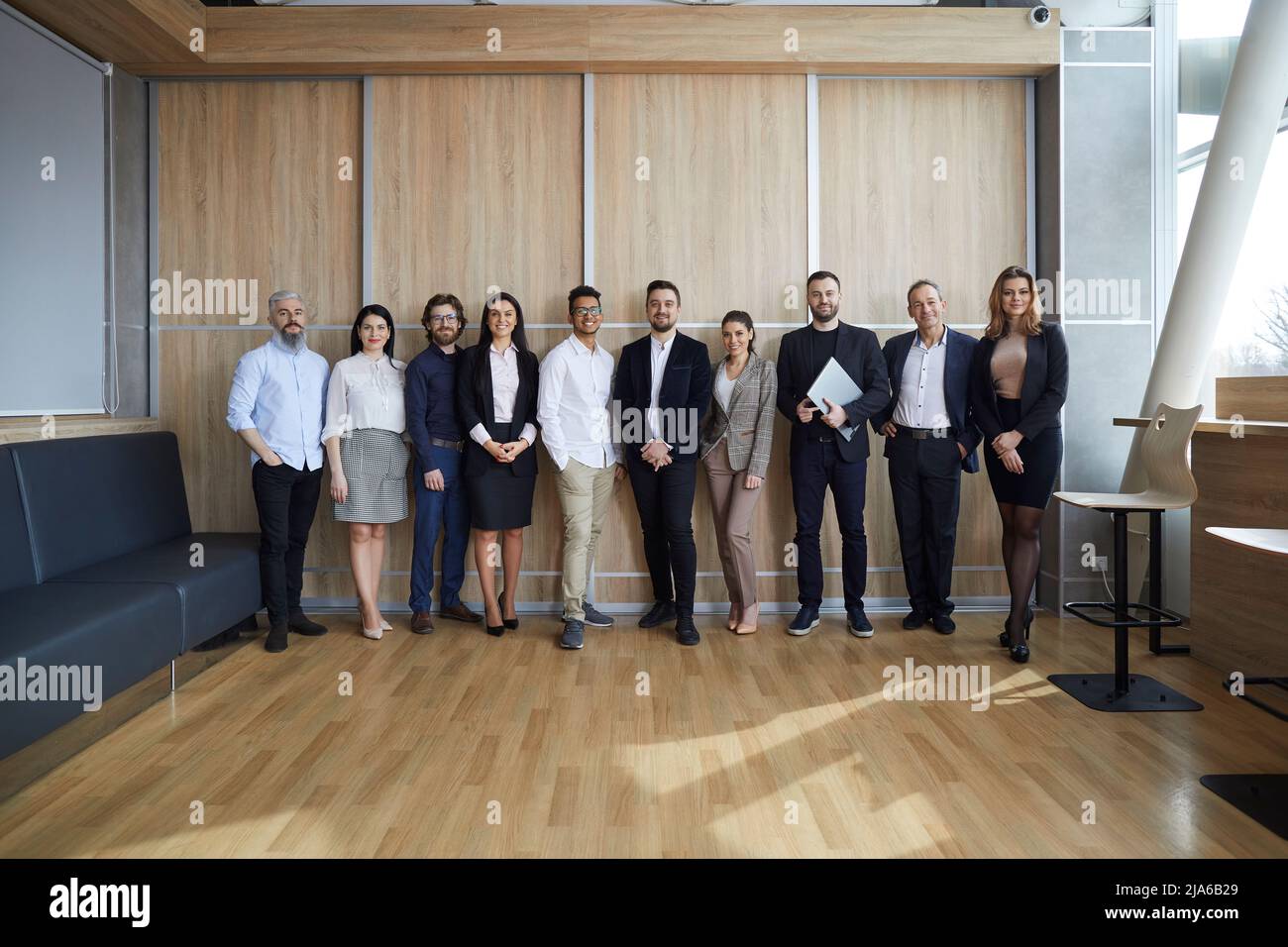 Ein vielfältiges Team von glücklichen Unternehmern oder Firmenmitarbeitern steht in einem modernen Büro Stockfoto