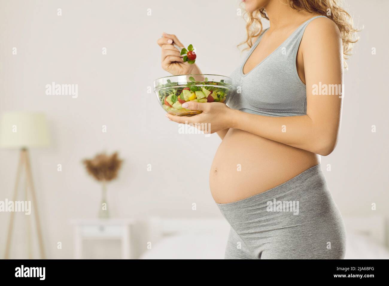 Werdende Mutter mit großem Bauch kümmert sich um ihre Gesundheit und isst frische Gemüsesalate Stockfoto