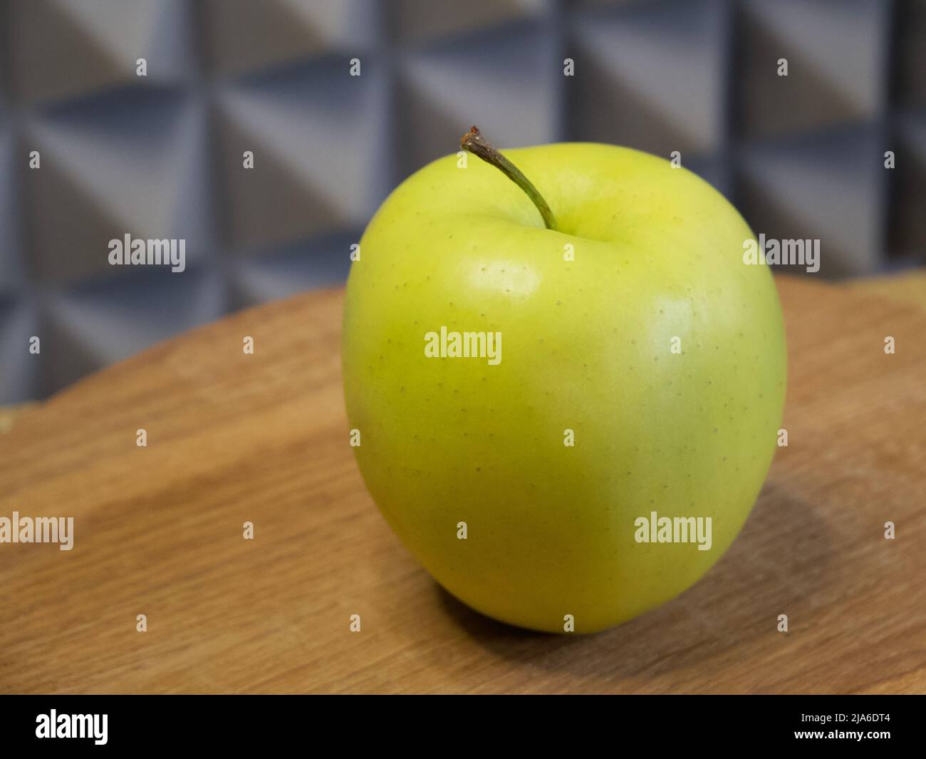 Golden Delicious ist ein gelber Apfel, einer der 15 beliebtesten Sorten in den Vereinigten Staaten. Ein einzelner Apfel auf einer Holzoberfläche, Nahaufnahme. Stockfoto
