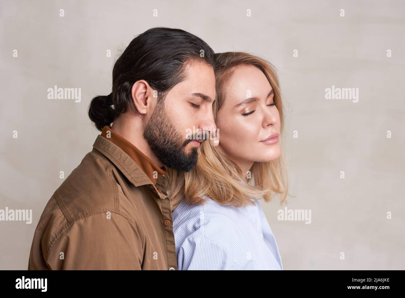 Mittleres Nahaufnahme-Studioporträt von schönen verliebten jungen Menschen, die nahe beieinander stehen, mit geschlossenen Augen, Kopierraum Stockfoto