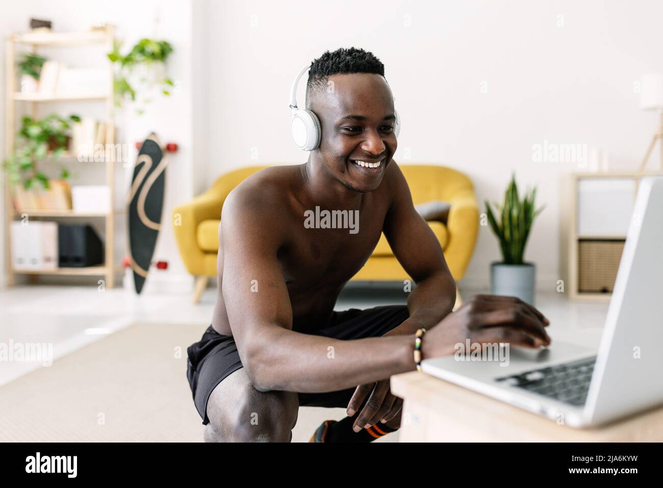 Glücklicher junger afrikanischer Mann sucht Training Video Fitness-Programm auf Laptop Stockfoto