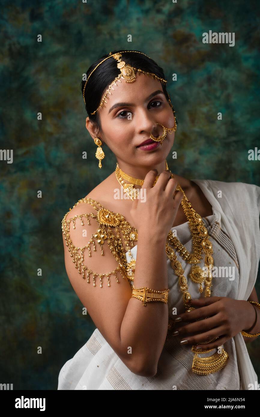 Indisches weibliches Modell mit weißem Saree und Goldschmuck in einem traditionellen bengalischen Saree-Look oder Binodini-Look, Saree-Modell, indische Ethnie Stockfoto