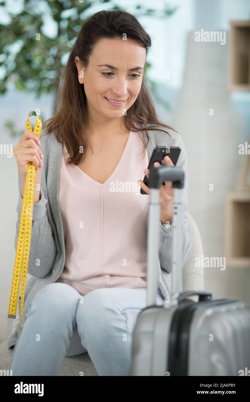 Brunette Frau misst ihr Handgepäck, bevor sie in den Urlaub geht Stockfoto