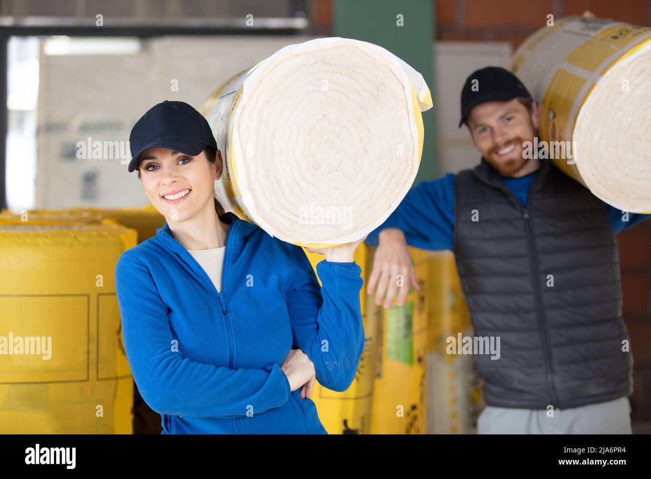 kaukasische Bauarbeiter mit Rollen aus Isoliermaterial Stockfoto