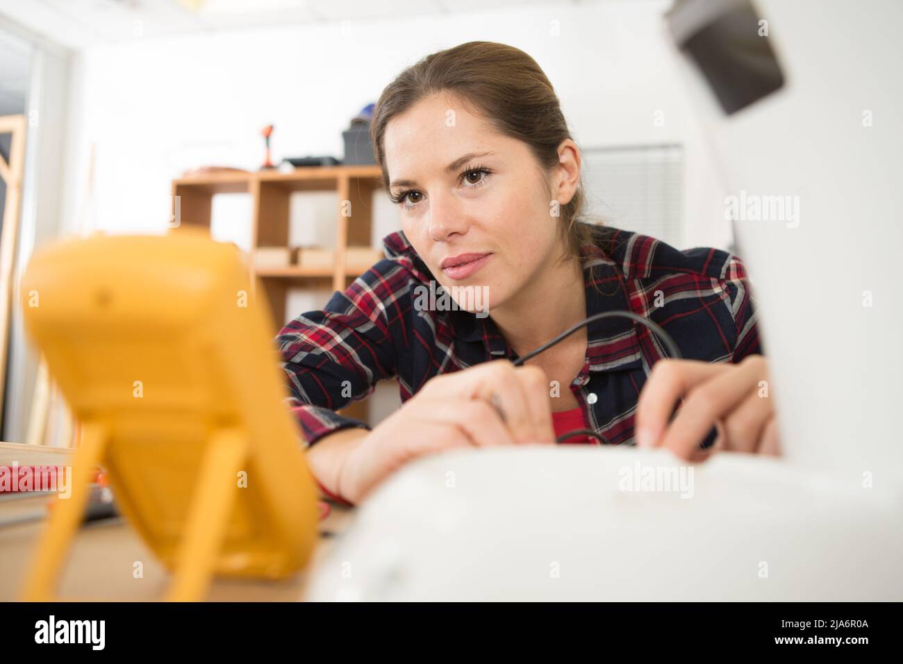 Frau, die ein Gerät mithilfe eines Multimeters gefunden hat Stockfoto
