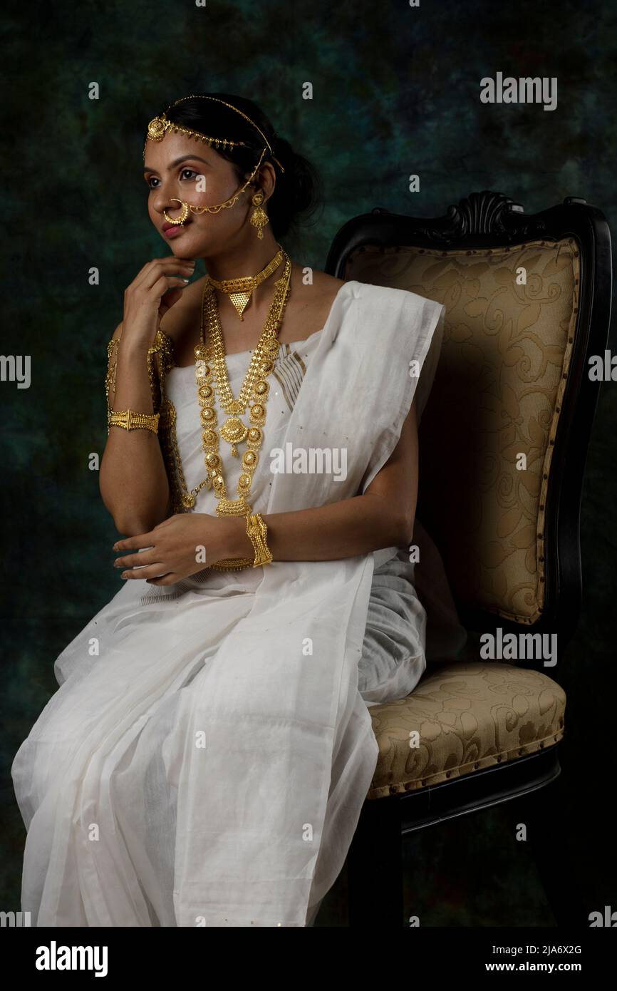 Indisches weibliches Modell mit weißem Saree und Goldschmuck in einem traditionellen bengalischen Saree-Look oder Binodini-Look, Saree-Modell, indische Ethnie Stockfoto