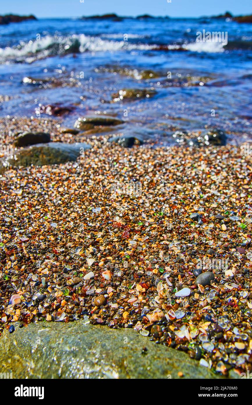 Strand mit Wellen und gefüllt mit glatten Stücken aus buntem Glas Stockfoto