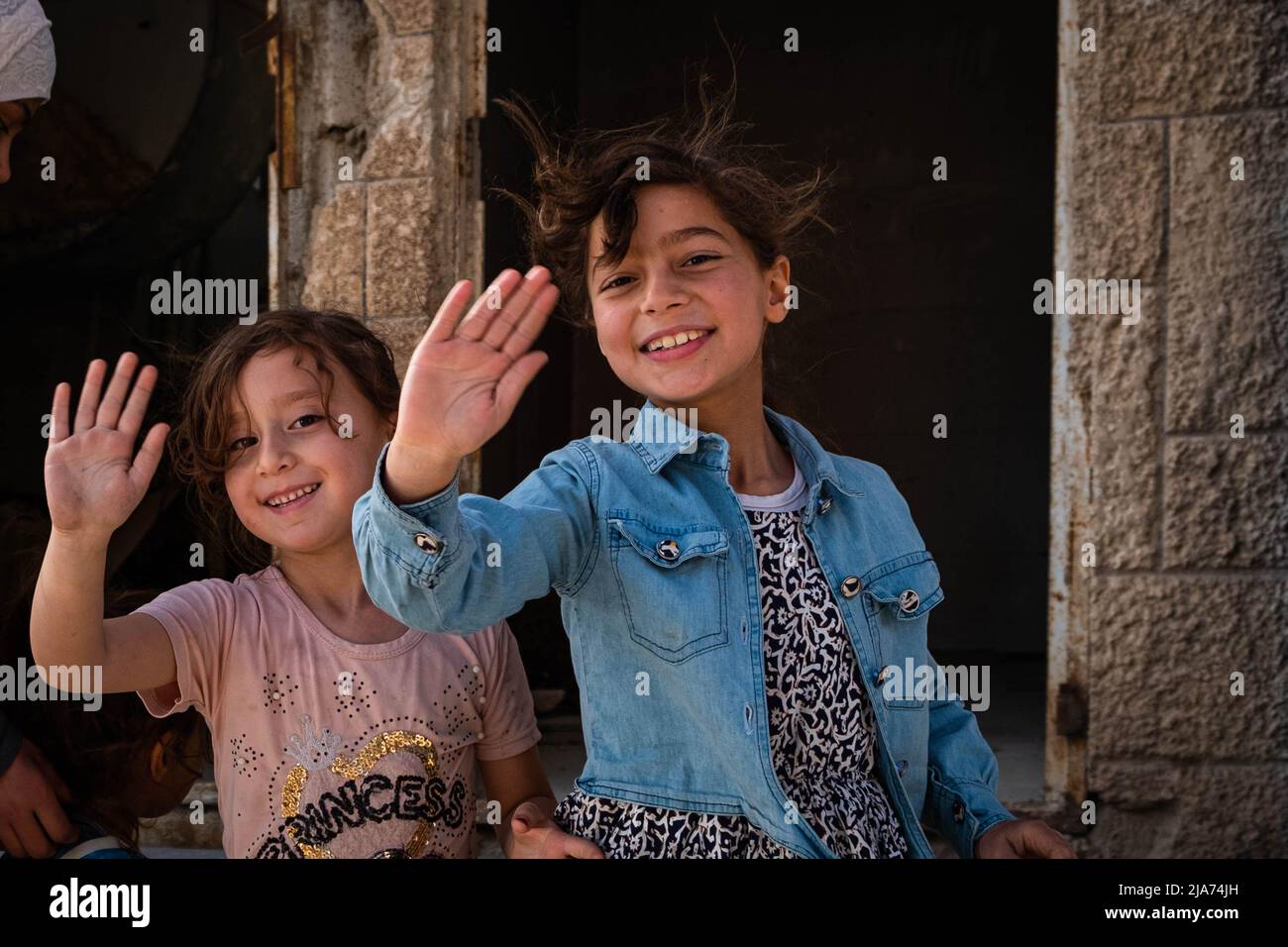 Syrische Kinder winken nach dem Bürgerkrieg in Darayya mit ihren Händen und lächeln. Stockfoto