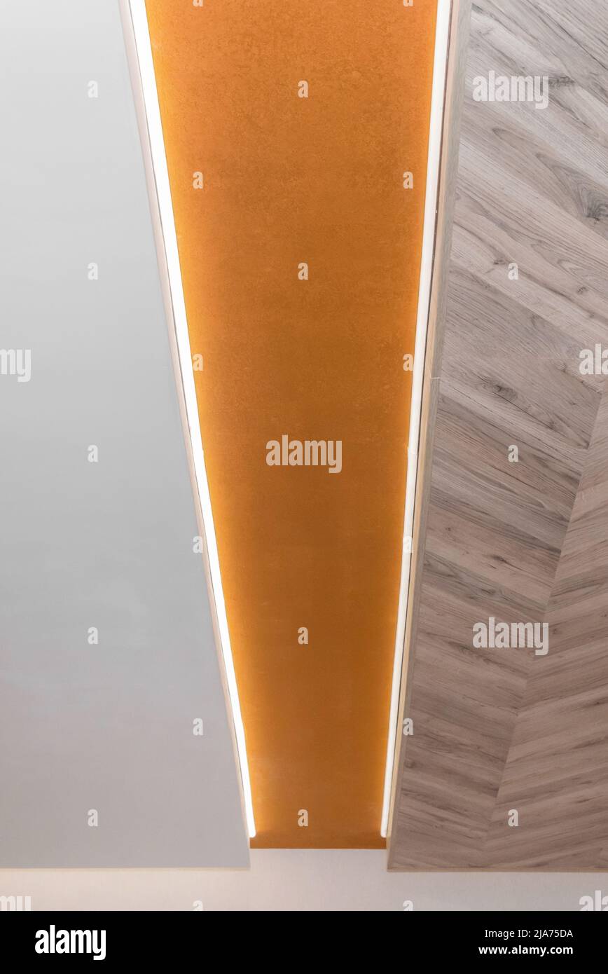 Holzlaminat Abstraktes Deckendesign Moderne Innenarchitektur Hintergrundstruktur mit LED Lineare Lichtdekoration. Stockfoto