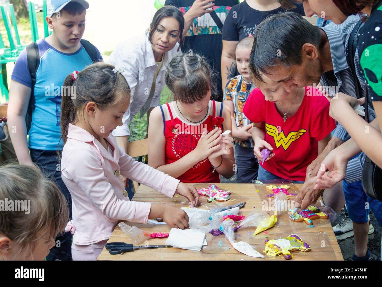 Zaporizhia/Ukraine- 19. Juni 2021: Kinder, die an Kunst- und Handwerkswerkstatt im Freien teilnehmen, dekorieren Kuchen mit farbenfroher Glasur. Kinder kreativ Stockfoto