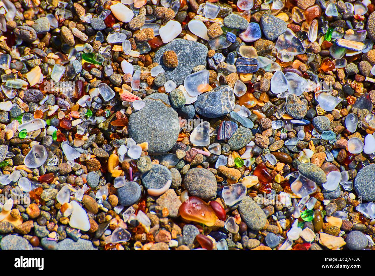 Strandkiesel aus glatten, bunten Felsen, die die Küste bedecken Stockfoto