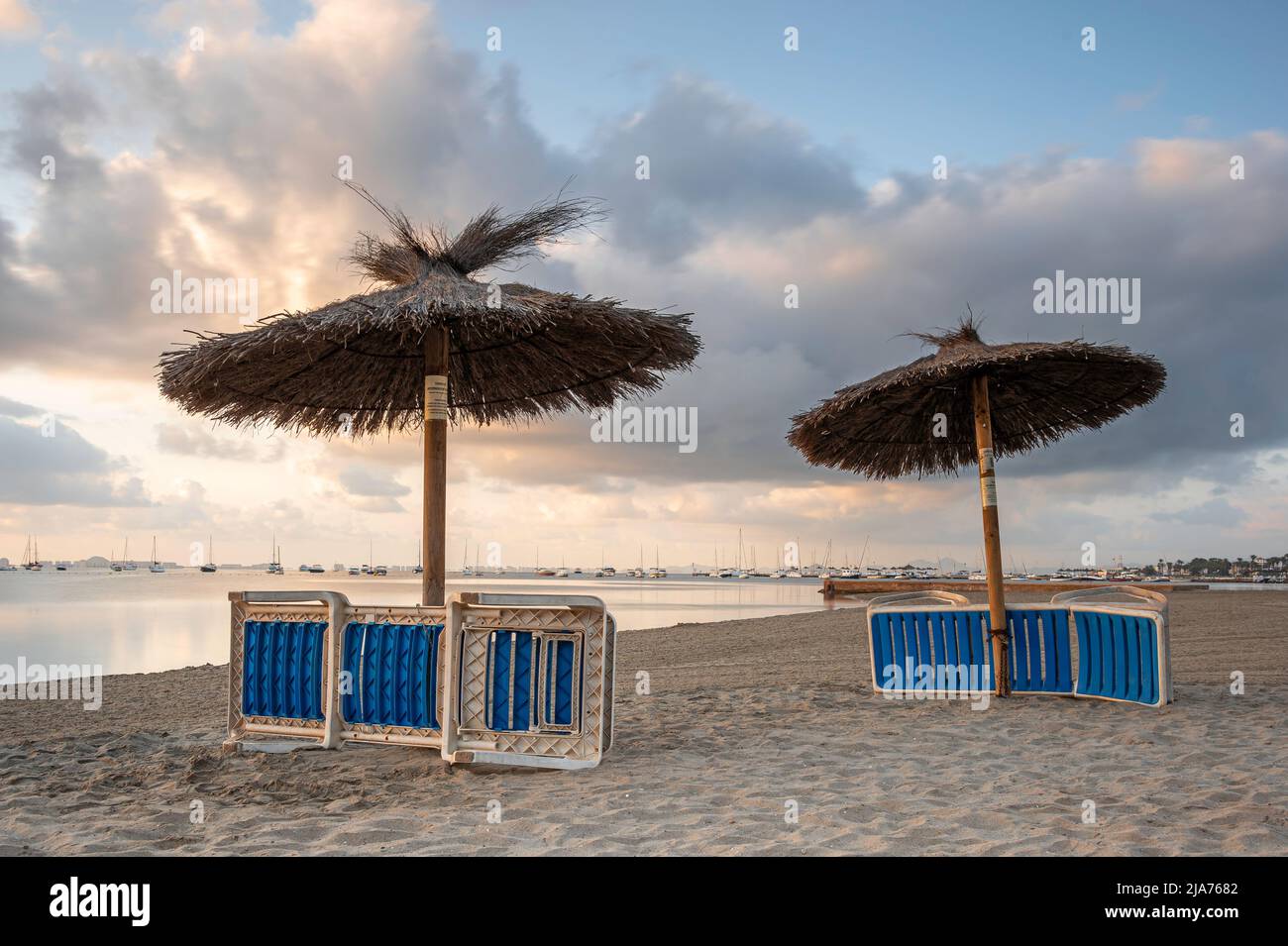 Liegen und Sonnenschirme, an einem spanischen Strand, für den Abend abgestellt Stockfoto