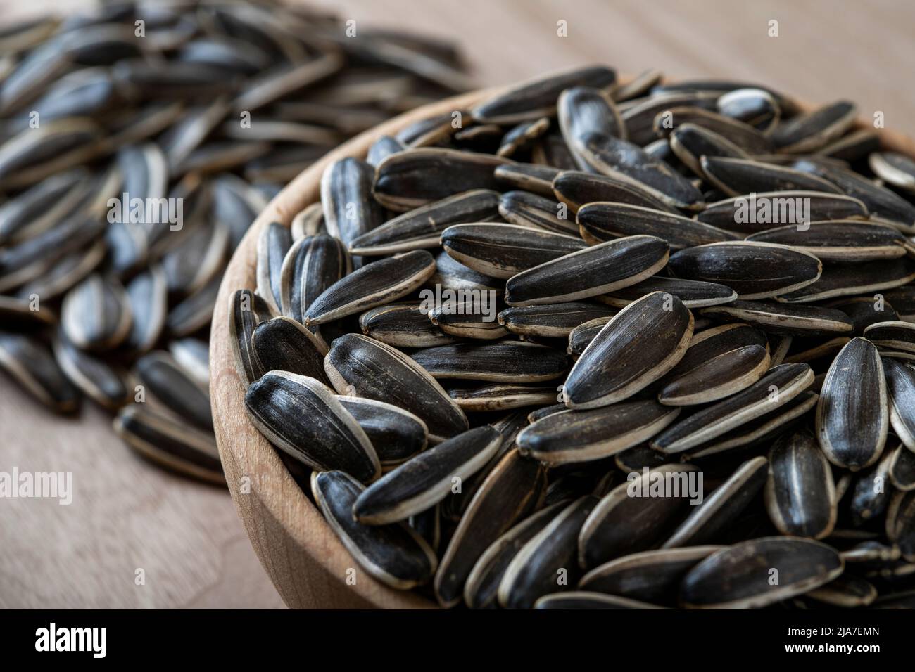 Schwarze Sonnenblumenkerne in einer Schüssel auf Holzgrund Stockfoto
