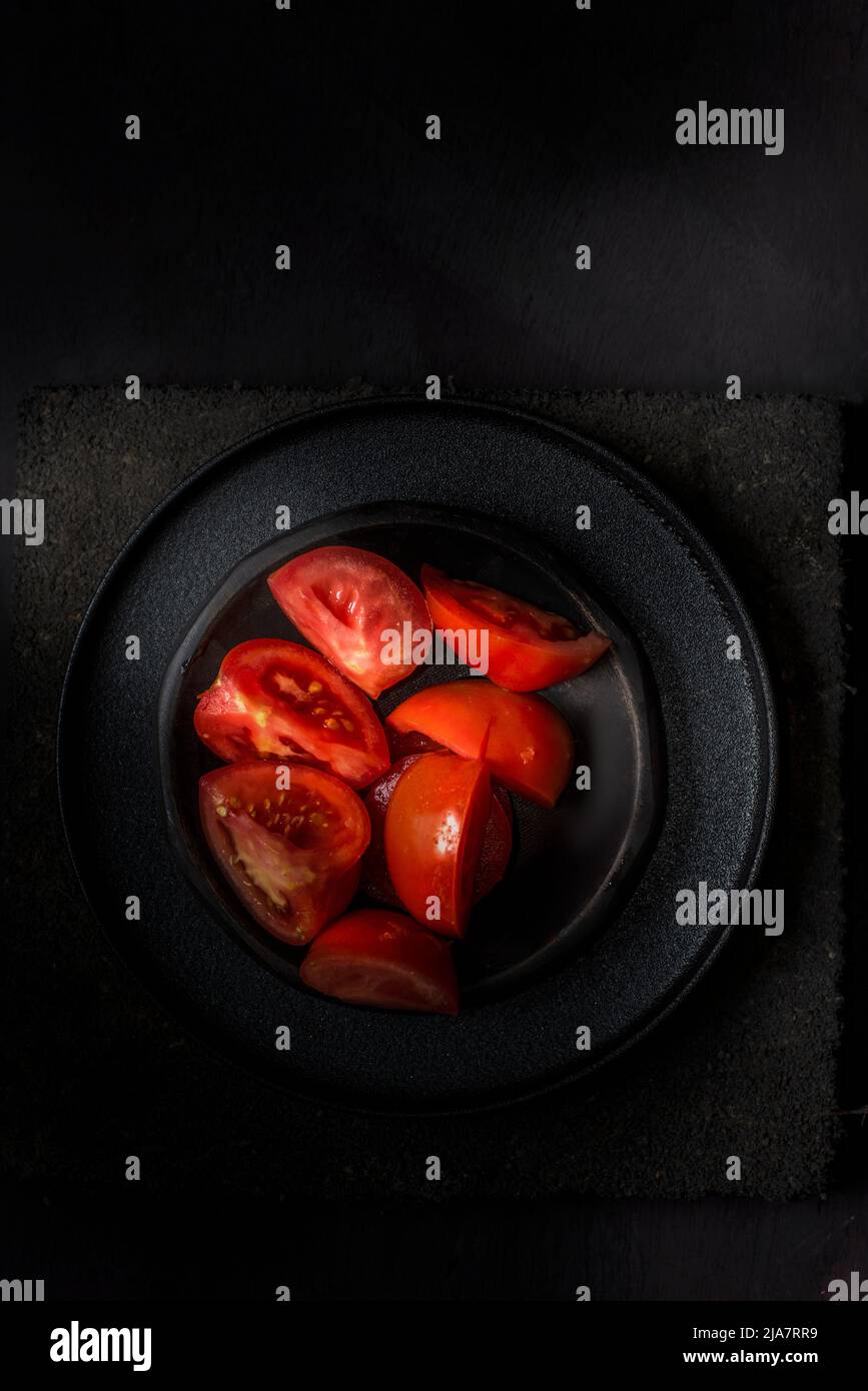 Tomatenscheiben auf einem schwarzen Teller Stockfoto
