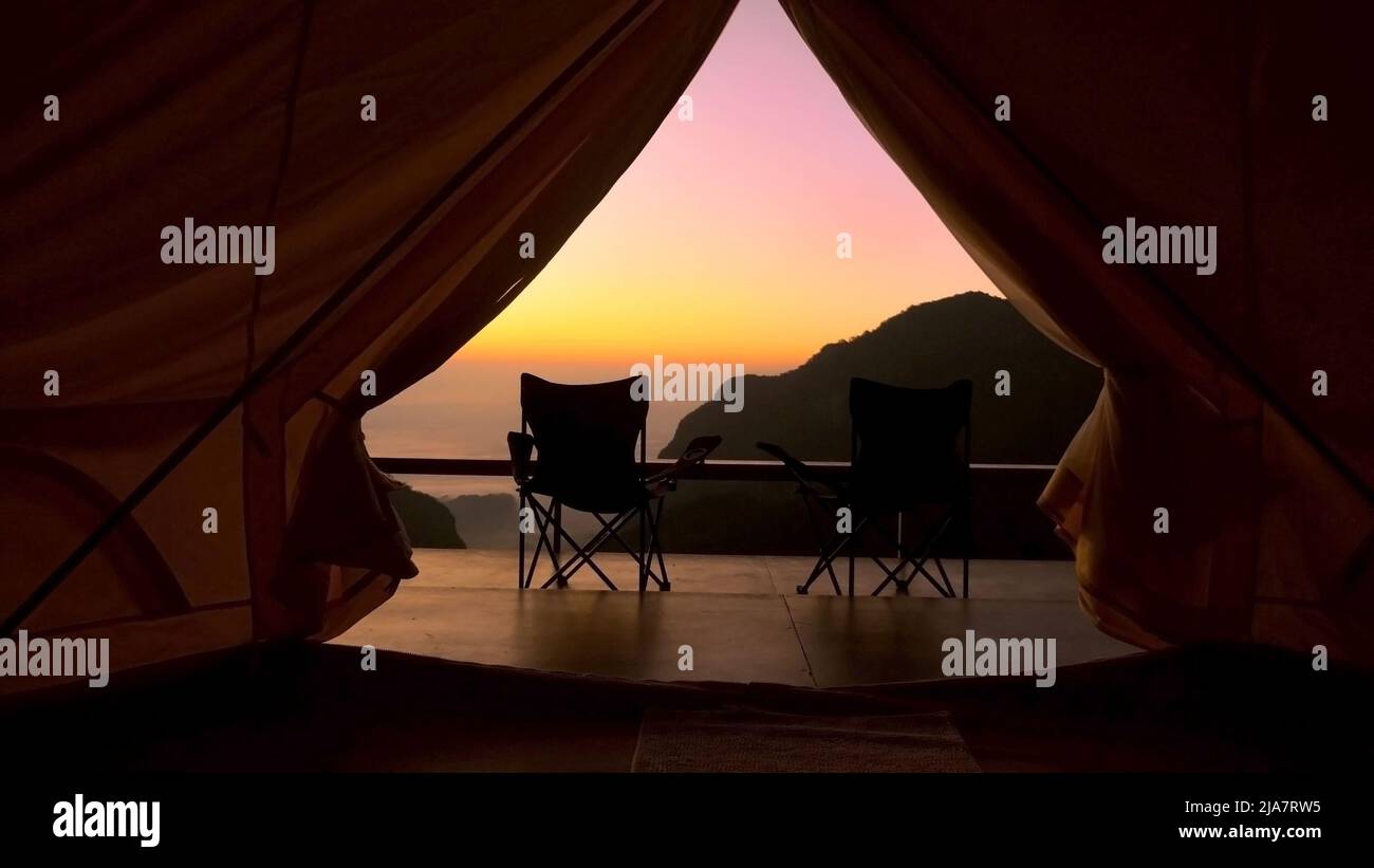 Touristenzelt im Camp mit Blick auf die Berge bei Sonnenaufgang. Blick vom Zeltlager auf erstaunlichen Sonnenaufgang mit Bergen und zwei Klappstuhl Stockfoto