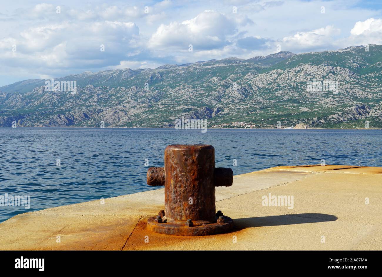Alte rostige Anlegestelle auf dem Seehampe vor einem hohen Berg Stockfoto