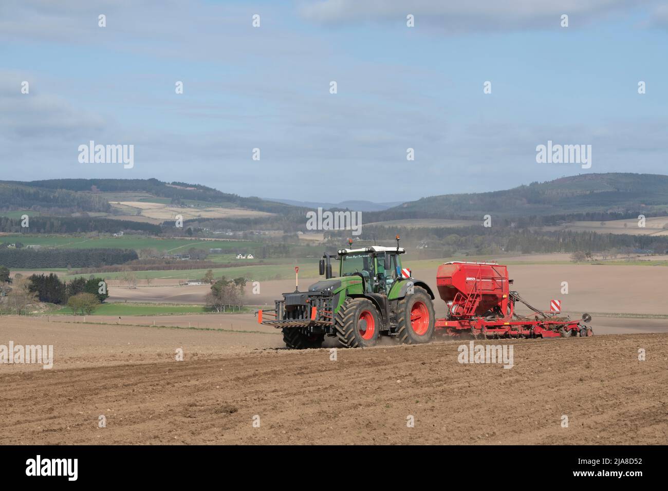 Eine landschaftlich reizende Agrarlandschaft in Aberdeenshire, mit einem Traktor- und Saatbohrer, der in einem gepflügten Feld in Betrieb ist, und Blick über das dahinter liegenden Farmland Stockfoto