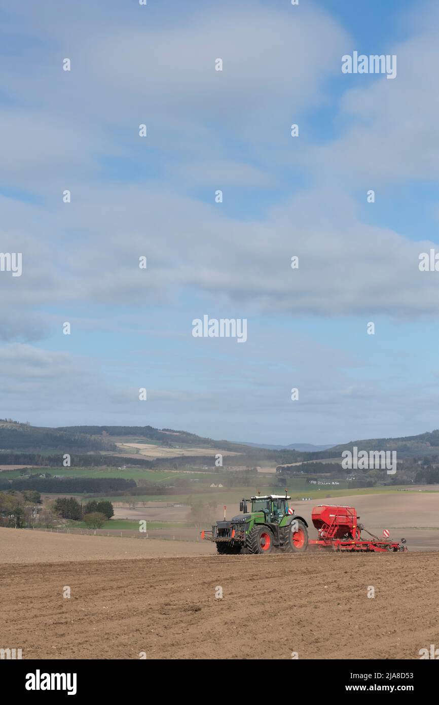 Ein grüner Fendt-Traktor und eine rote Horsch-Sämaschine säen im Frühjahr ein gepflügtes Feld mit Blick auf eine landschaftlich reizende Farmlandschaft in Aberdeenshire Stockfoto