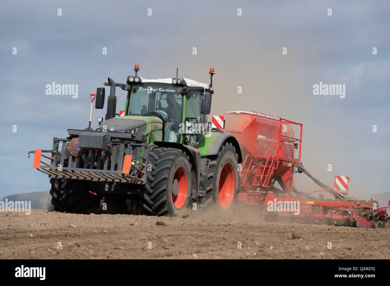 Ein grüner Fendt-Traktor, der Staubwolken erzeugt, während er mit einer Horsch Universal-Sämaschine in einem trockenen gepflügten Feld arbeitet Stockfoto