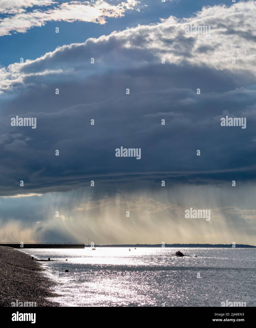 Regenvorhänge, die von einem entfernten Duschkopf über die Isle of Sheppey fielen, und Hampton Pier in der Ferne. Stockfoto