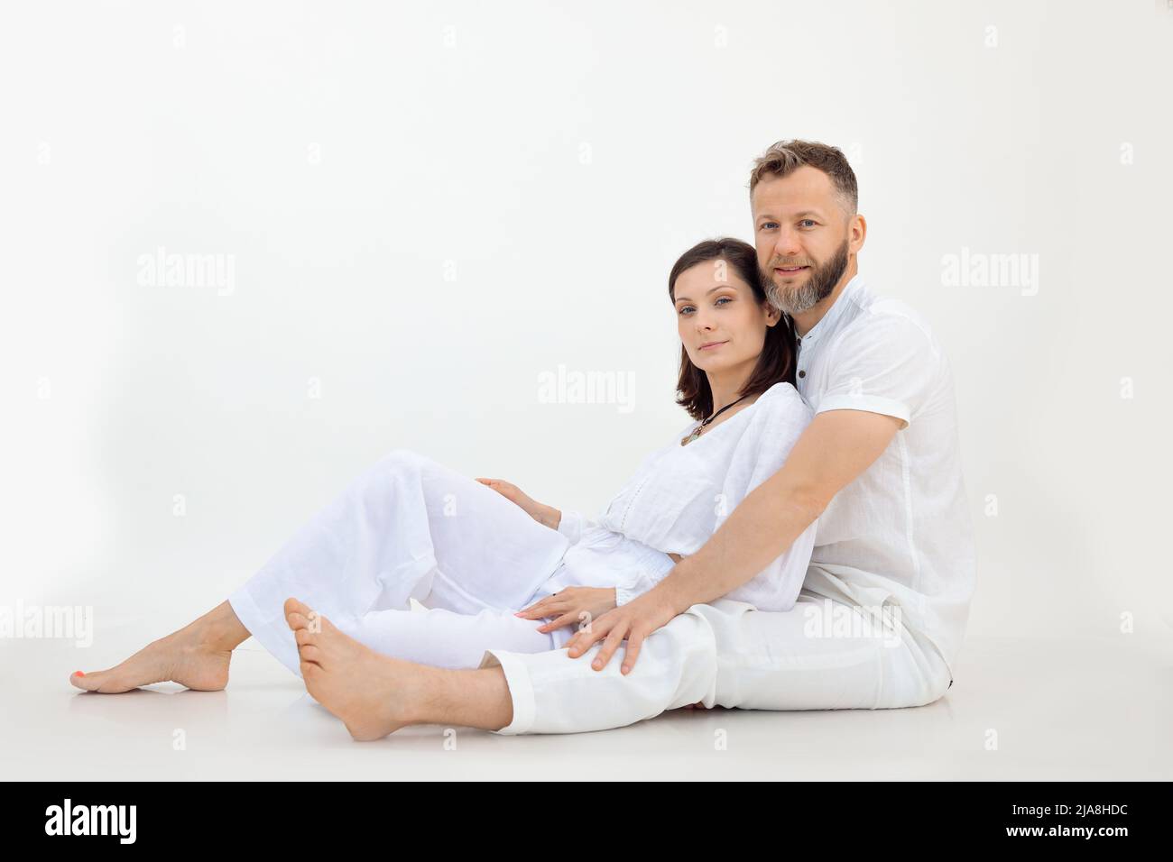 Frau und Mann aus der Studioaufnahme, Familie schauen sich die Kamera in weißem Outfit an. Gesunder, spiritueller, meditierischer Lebensstil. Speicherplatz kopieren Stockfoto