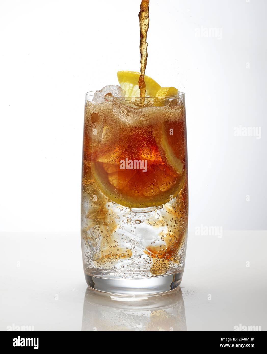 cola ergießt sich in ein Cocktailglas auf weißem Hintergrund Stockfoto