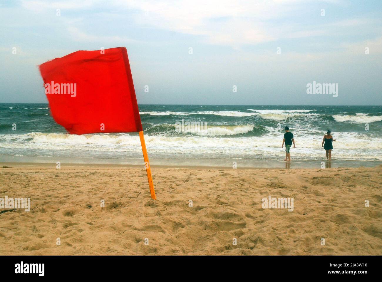 Zwei Menschen waten in der rauen Brandung des Ozeans, trotz der Warnung vor der roten Flagge am Robert Moses Beach auf Long Island Stockfoto