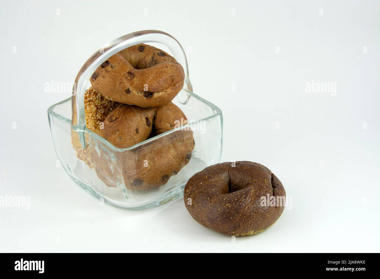 Verschiedene Zimt-Rosinen, Sesamsamen und Pumpernickel-Bagels im Glaskorb Stockfoto