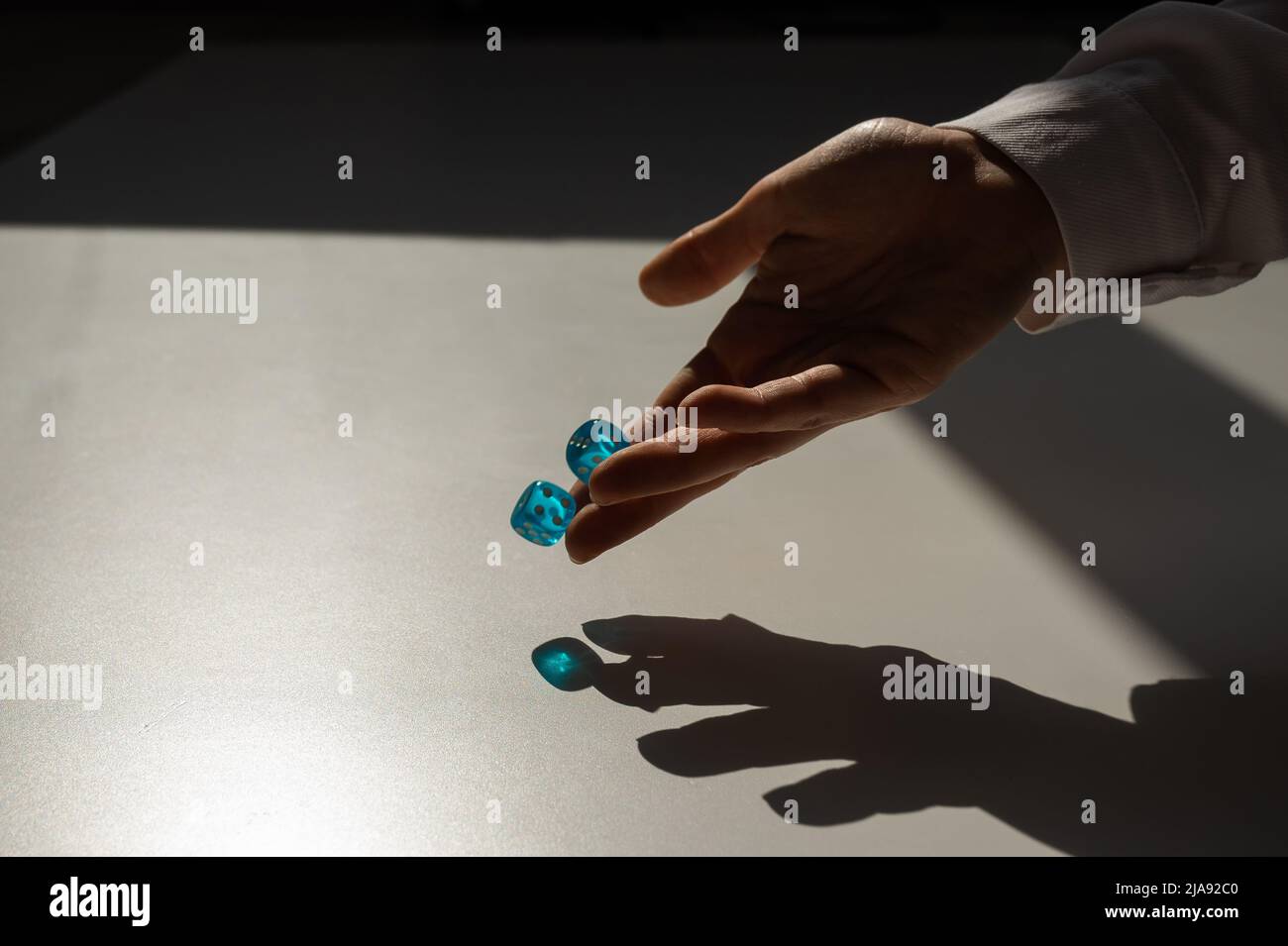Frau wirft ein Paar blaue transparente Würfel. Stockfoto