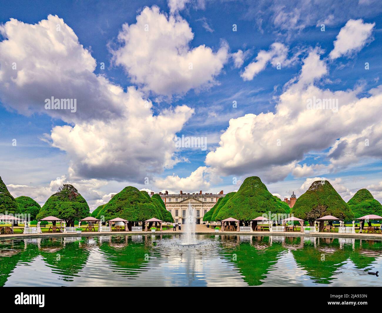 9. Juni 2019: Richmond, Großbritannien - Hampton Court Palace und der East Garden, mit Topiary im See reflektiert und einem kleinen Brunnen, Besucher herumlaufen Stockfoto