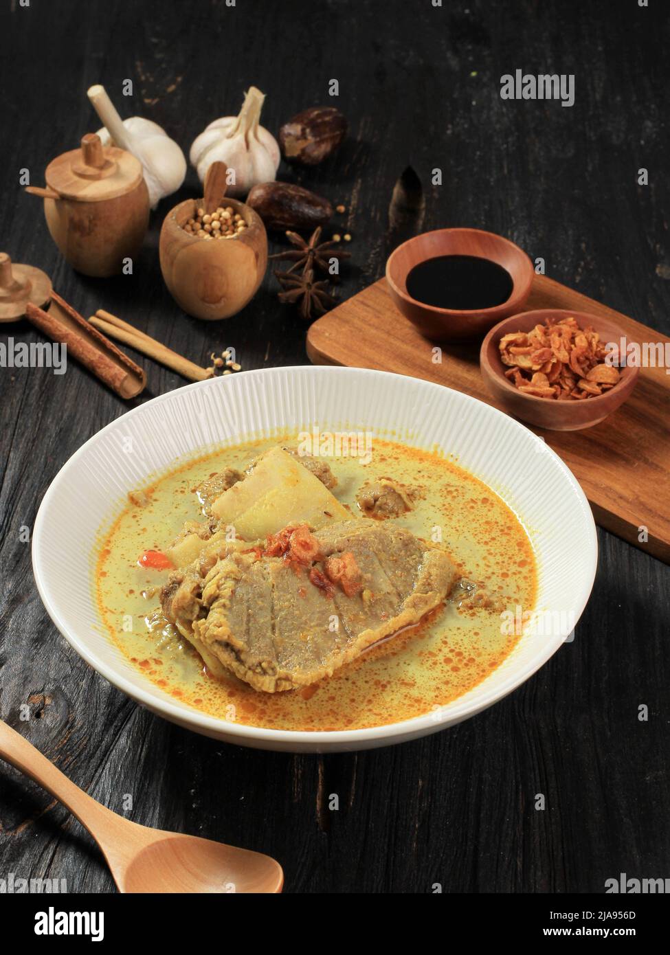 Gulai Kambing ist die traditionelle indonesische Hammelcurry-Suppe. Serviert auf einer weißen Schüssel über dem Holztisch Stockfoto