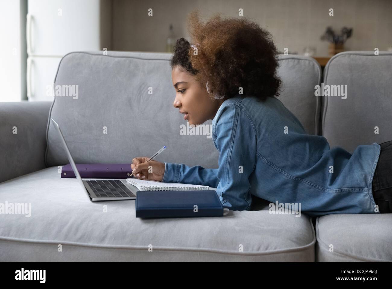 Fokussiertes schwarzes Schulschülerin Mädchen in Kopfhörern, das zu Hause studiert Stockfoto