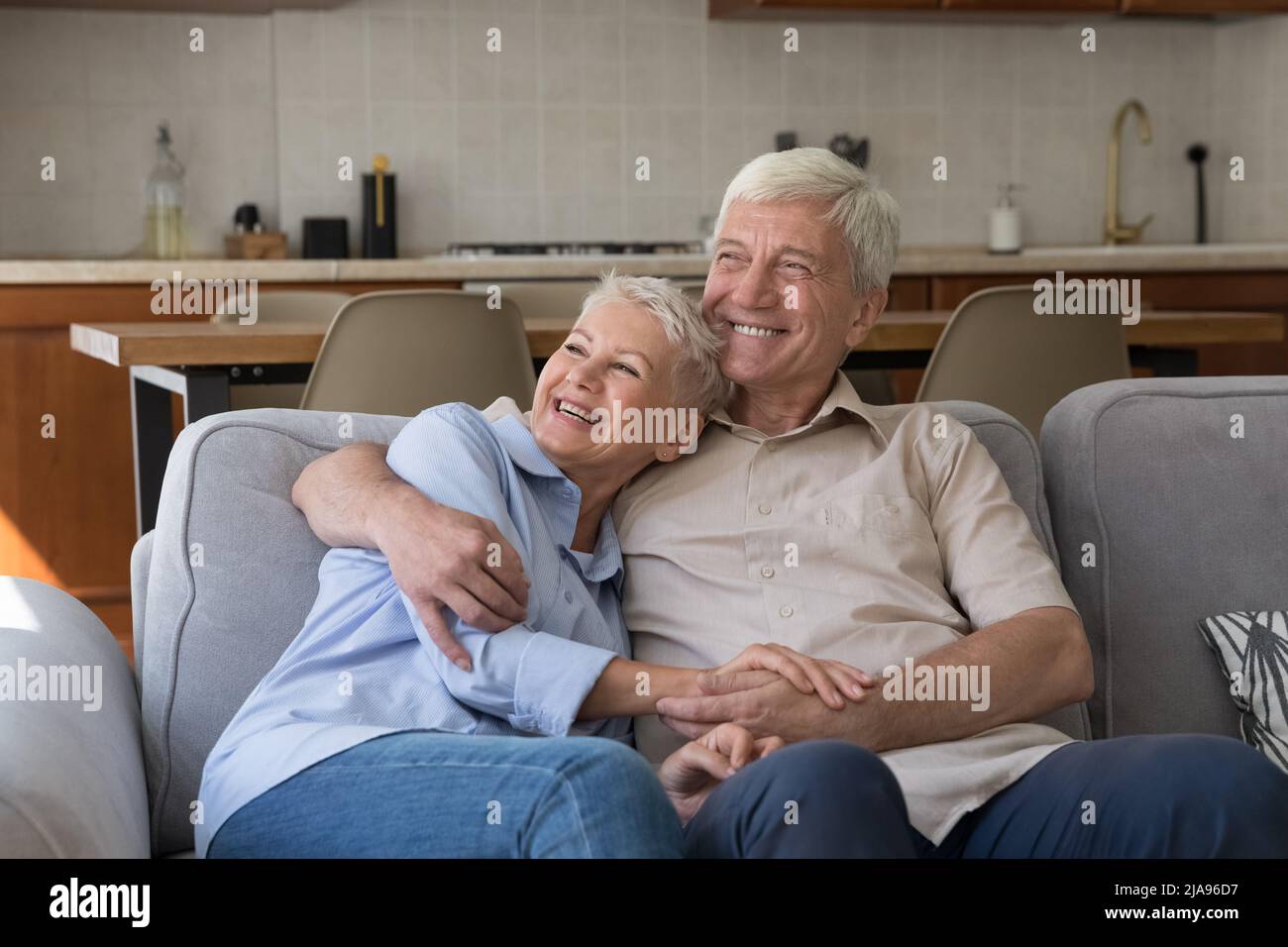 Glücklich gealterte Ehegatten Rentner kuscheln auf dem Sofa Blick in die Ferne Stockfoto