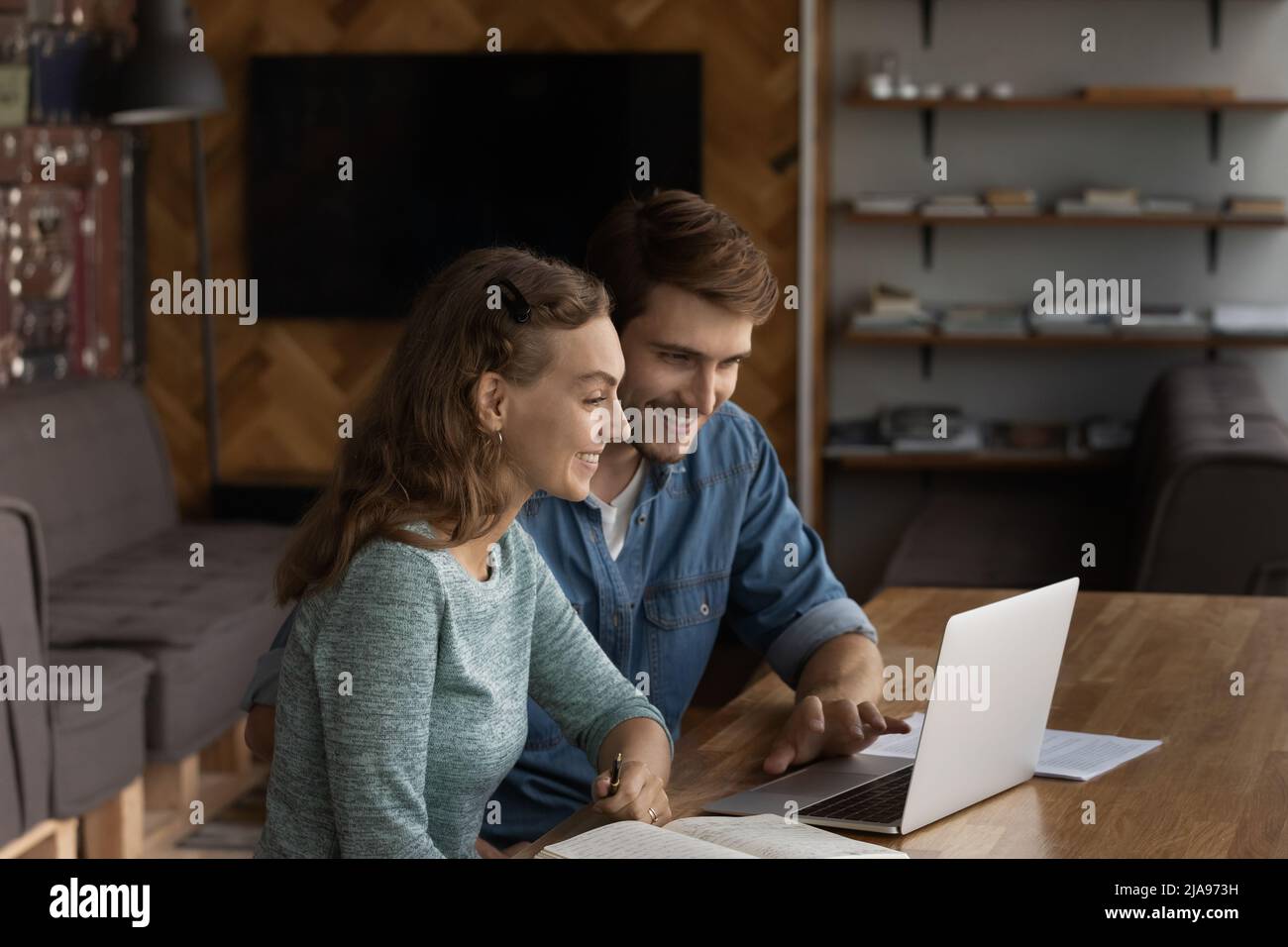 Zwei glückliche Geschäftsleute, die in einem modernen Büro einen Laptop verwenden Stockfoto