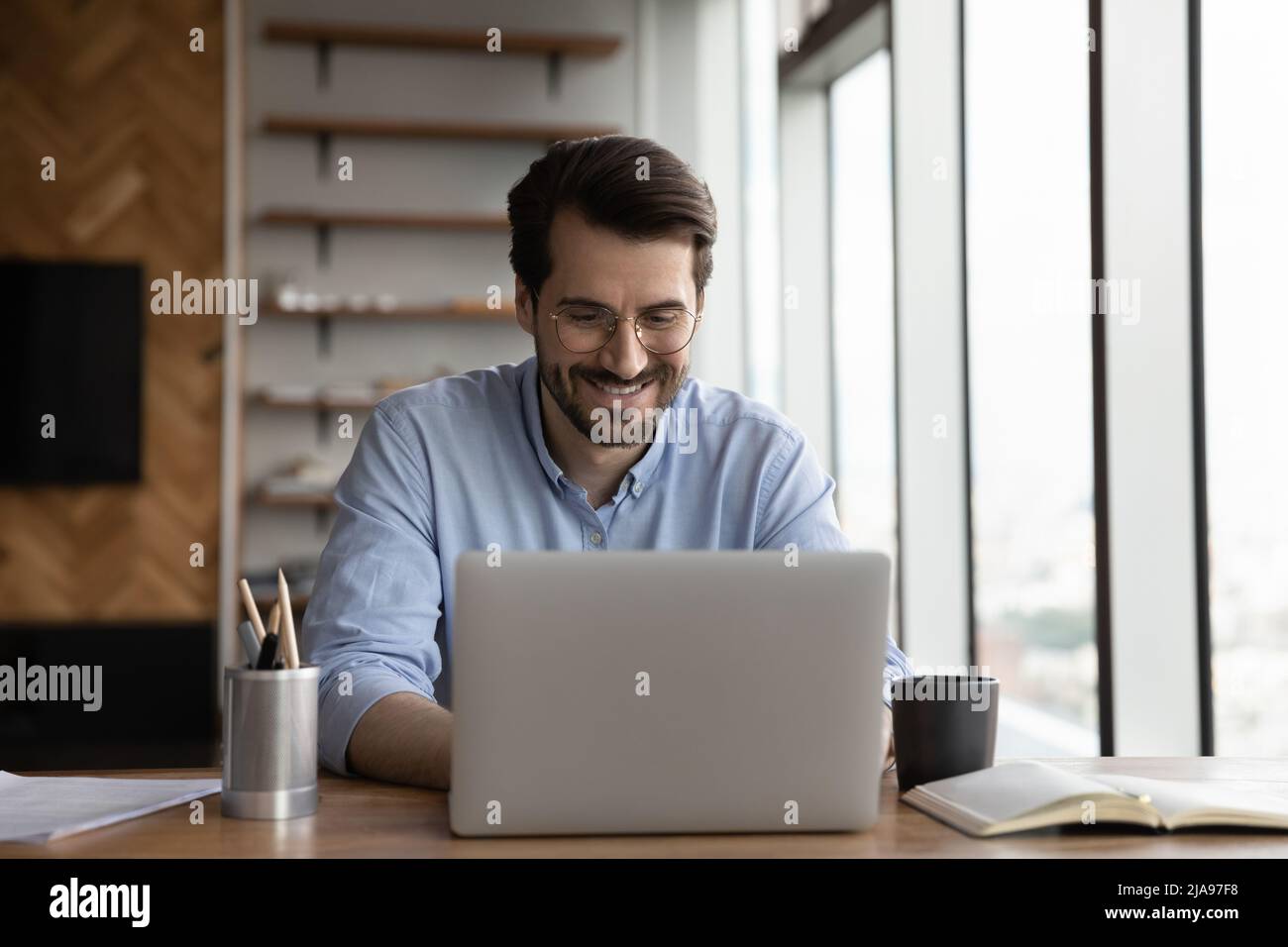 Glücklicher Business-Projektmanager, der von zu Hause aus mit einem Laptop arbeitet Stockfoto