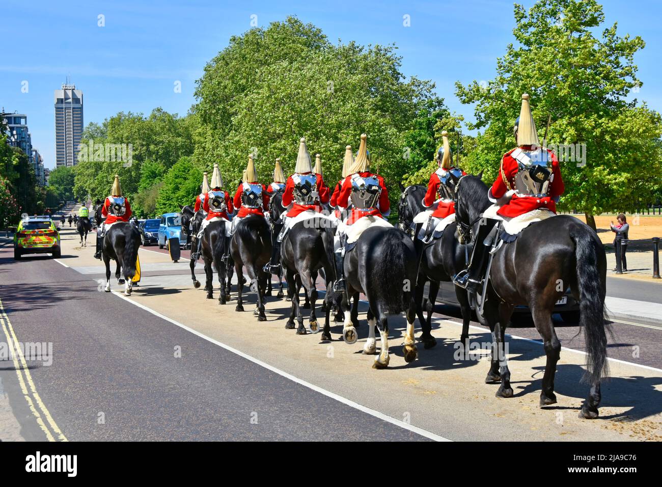 Household Cavalry Life Guards und Polizeieskorte in South Carriage Drive kehren zum Hyde Park zurück Knightsbridge Barracks Tower Block entfernt von London England Großbritannien Stockfoto
