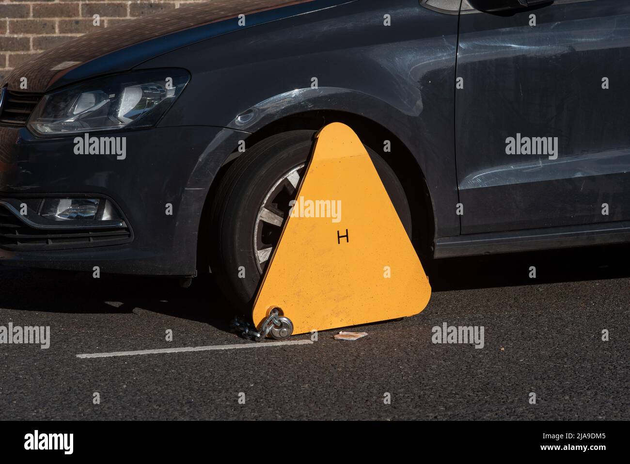 Leuchtend gelbe Radklemme an einem Auto befestigt. Jemand hat einen schlechten Tag. Stockfoto