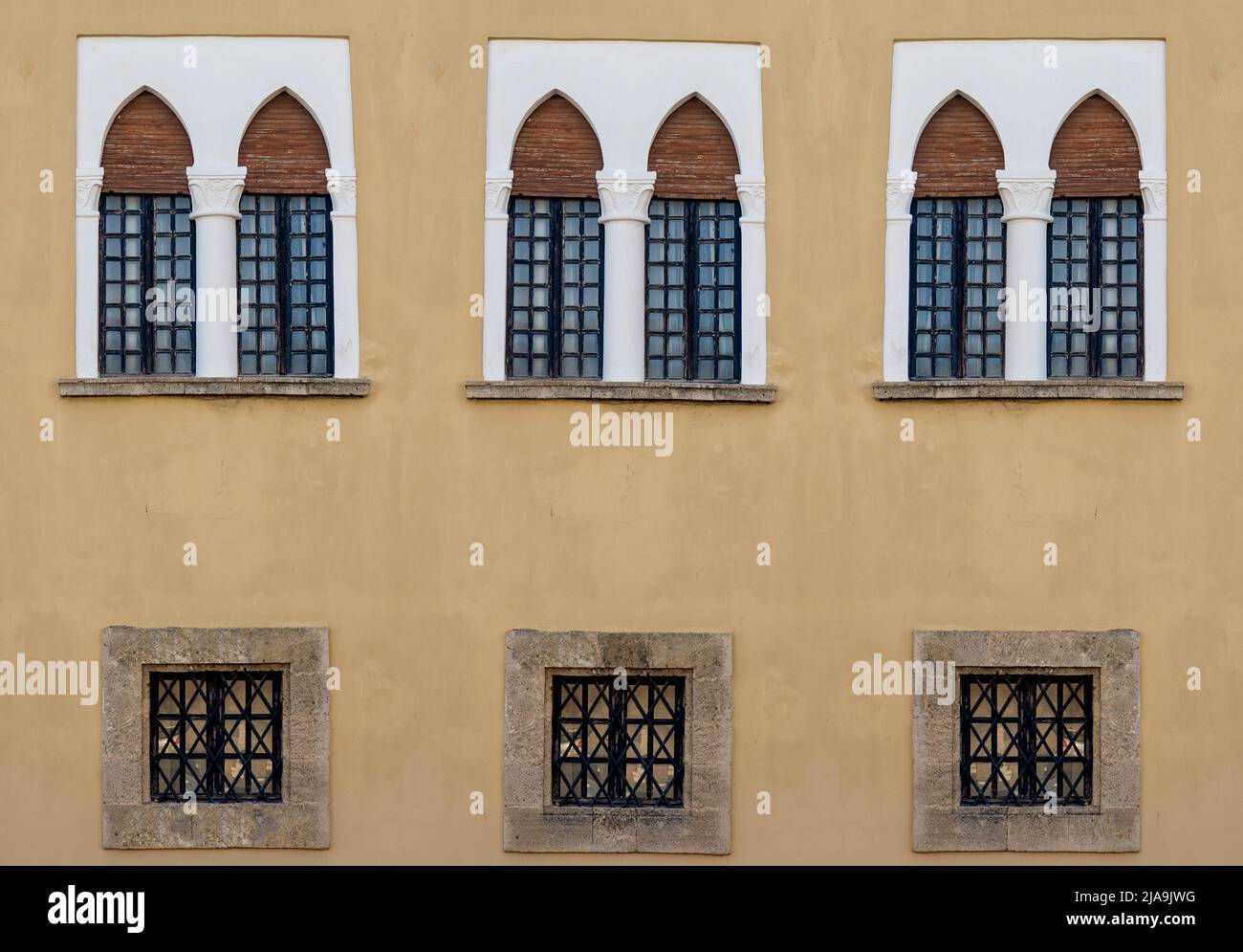Antike Holzfenster mit gewölbter Form auf einer bemalten Wand. Stockfoto