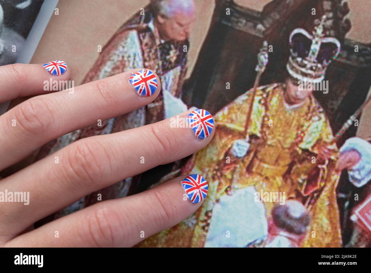 Frau mit Fingernägeln, gemalt mit der britischen Flagge, die auf dem OK-Magazin ruht, mit einem Bild aus der Krönung der Königin. Platinum Jubilee Juni 2022 Stockfoto