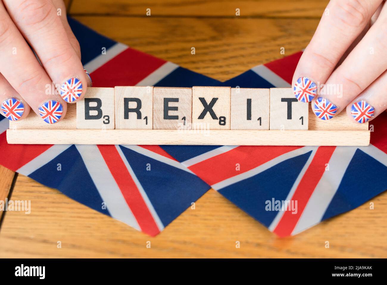 Die Fingernägel der Frau sind mit Union Jacks geschmückt, die auf britischen Flaggen abgekratzt Buchstaben halten, die den Brexit ausweisen. Konzept - Brexit-Feier Stockfoto