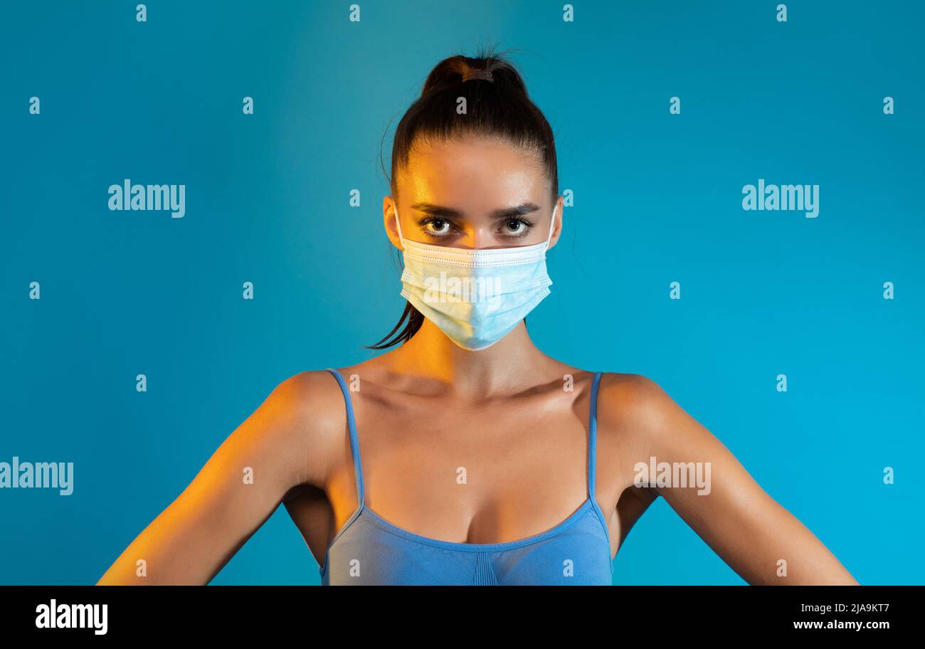 Sportliche Dame Mit Chirurgischer Gesichtsmaske Auf Blauem Hintergrund Stockfoto