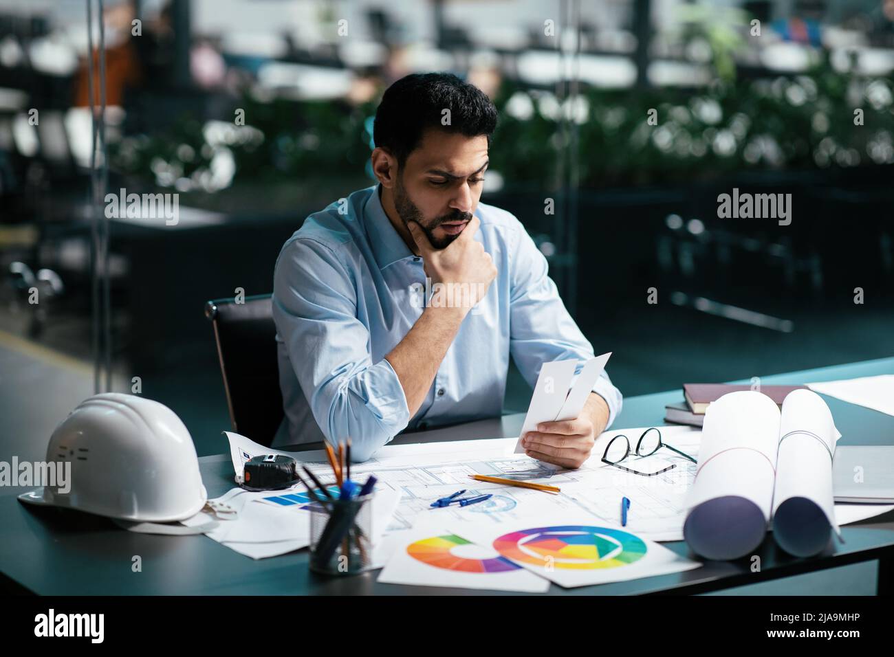Nachdenkliche Millennial islamischen männlichen Ingenieur in Brille mit Bart denken an Farbe für Projekt am Arbeitsplatz Stockfoto